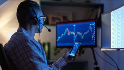 investor looking at stock charts on phone and computer