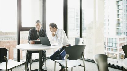 A pair of financial advisers work together at a table in an office.