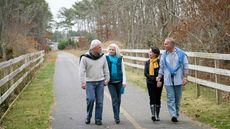 Two couples walk on a path side-by-side.