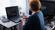 A woman at a home office looks at stock market performance. 