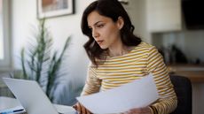 Woman reviewing paperwork on laptop