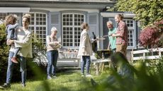 A multigenerational family have a barbecue outside the parents' home.